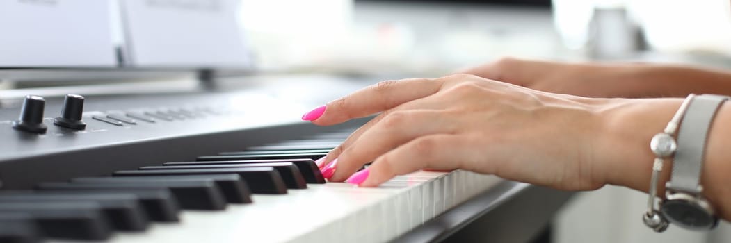 Female hand presses keys of synthesizer and learns to play. Piano lessons concept