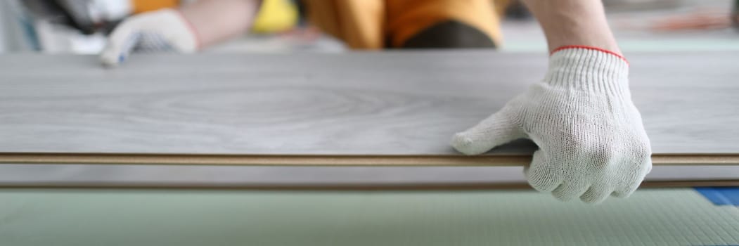 Closeup of work of master on installation of flooring. Male hands working laying laminate on floor