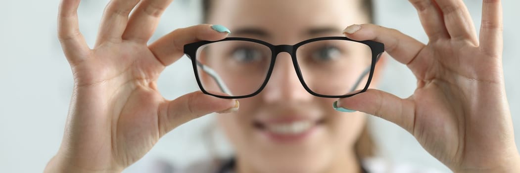 Female ophthalmologist doctor holding glasses in ophthalmology clinic. Optics for vision farsightedness myopia astigmatism concept