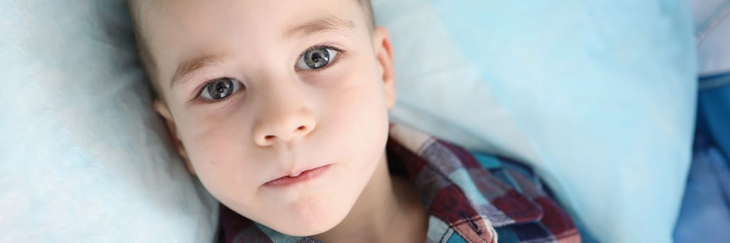 Portrait of cute little boy in colored shirt looking at camera with serious attentive face. Calm thoughtful facial expression concept