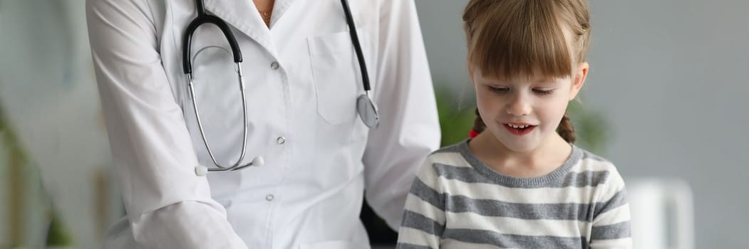 Little beautiful girl communicates with female doctor in clinic. Concept of children medical services and insurance