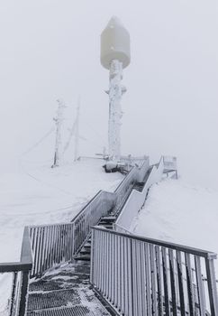 The stairway to the signal tower on mountain peak covered by snow in Switzerland.