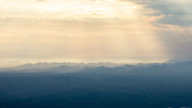 Landscape of sunbeam shining on blue mountain range before sunset.