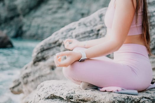 Young woman with black hair, fitness instructor in pink sports leggings and tops, doing pilates on yoga mat with magic pilates ring by the sea on the beach. Female fitness daily yoga concept