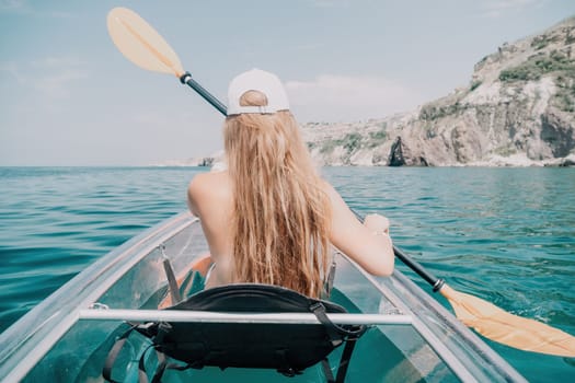 Woman in kayak back view. Happy young woman with long hair floating in transparent kayak on the crystal clear sea. Summer holiday vacation and cheerful female people having fun on the boat.