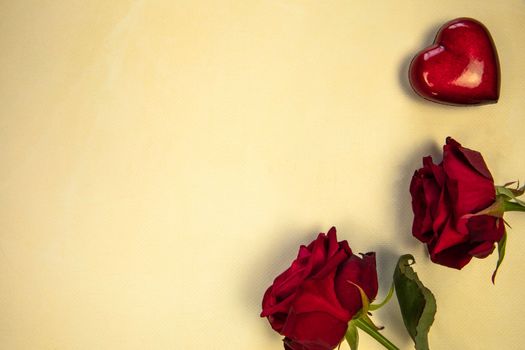 Flowers composition. Frame made of rose flowers and red heart on yellow background. Valentine's Day Mother's Day romantic background. Flat lay, top view, copy space.