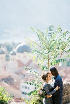 Groom kisses the forehead of bride in a blue dress on the observation deck over the city. High quality photo