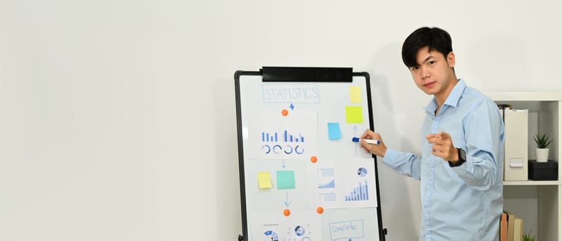 Confident asian man manager give business presentation about financial growth on whiteboard. Copy space for your text.