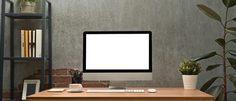 Stylish workplace white blank screen computer monitor on wooden desk. Blank screen for graphic display montage.