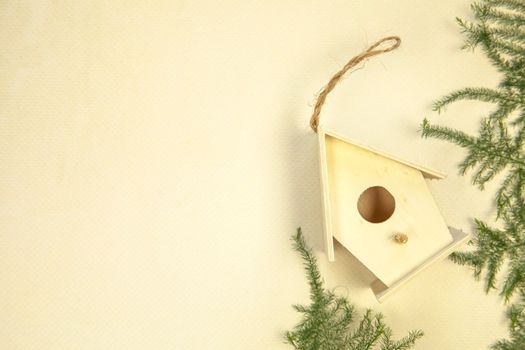 Beautiful bird house on beige background, top view. Space for text Spring concept wooden handmade birdhouse green leafs