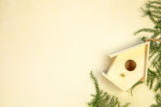 Beautiful bird house on beige background, top view. Space for text Spring concept wooden handmade birdhouse green leafs
