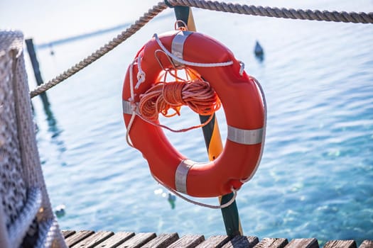 A red lifesaver on a wooden dock at Lake Garda, a popular tourist destination in Italy, symbolizing safety and security for water activities.