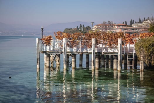 The beautiful landscape of Sirmione on the Garda Lake Riviera, with its crystal clear waters and stunning mountains in the distance.