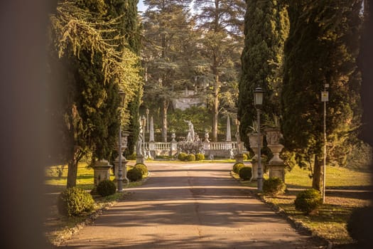 A stunning ancient villa at the end of a tree-lined avenue, showcasing luxury and opulence.