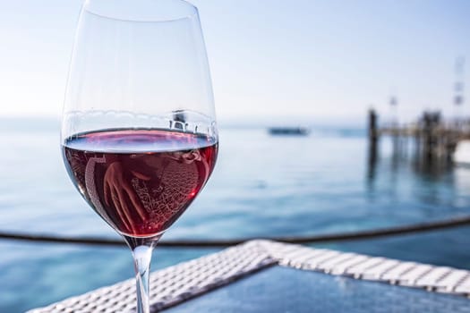 A wine glass placed on a table at a bar by the seafront with a view of the Riviera.