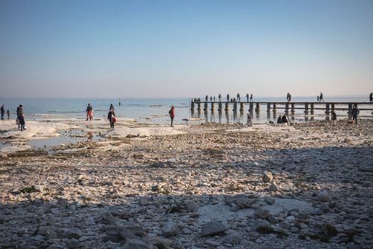 Sirmione, Italy 15 February 2023: A stunning landscape photo of a rocky beach in Sirmione, with the clear waters of Lake Garda in the background