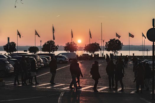 Sirmione, Italy 15 February 2023: Beautiful sunset over the stunning Garda Lake in Italy, with the sun reflecting on the calm water and creating a peaceful atmosphere. Perfect for travel projects.