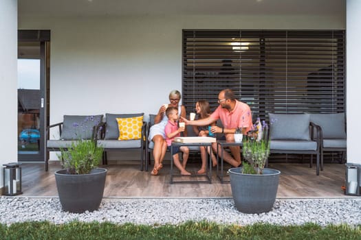 Happy caucasian family of four, mother father and children at home, outdoors playing on the grass, and indoors in the living room having fun as a family.