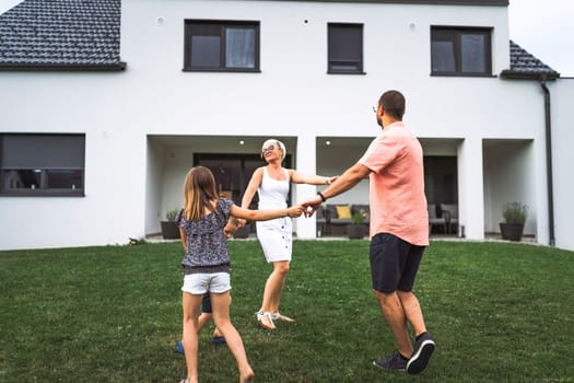 Happy caucasian family of four, mother father and children at home, outdoors playing on the grass, and indoors in the living room having fun as a family.