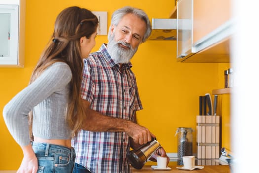 Young caucasian woman taking care of her grandfather, senior man with beard and grey hair. Granddaughter visiting her grandfather, spending quality time together.