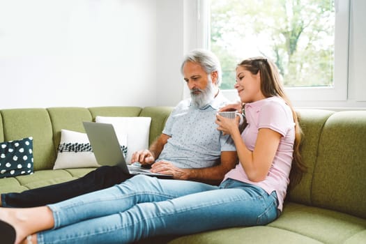 Young caucasian woman taking care of her grandfather, senior man with beard and grey hair. Granddaughter visiting her grandfather, spending quality time together.