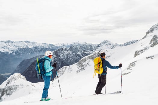 Mountaineer backcountry ski touring in the mountains. Ski touring in high alpine landscape with snowy trees. Adventure winter extreme sport. High quality photo