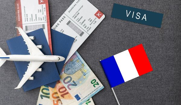 Flag of France with passport and toy airplane on wooden background. Flight travel concept.