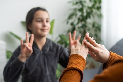 daughter talk with middle aged mother people using sign language, family sitting on armchair side view, teacher teach teenager deaf-mute girl to visual-manual gestures symbols concept image.
