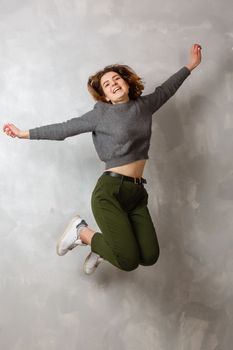 Full length portrait of a cheerful casual asian woman jumping isolated over gray background
