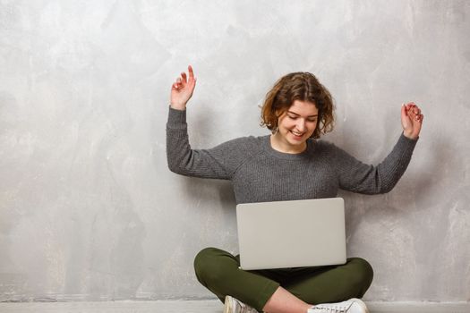 Smiling woman is pointing on laptop background