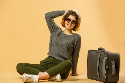 woman sitting near suitcase isolated on white background