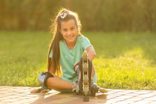 little girl wears roller skates on beautiful summer day in a park.