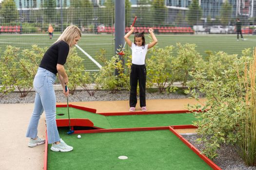 little girl and mother playing mini golf.