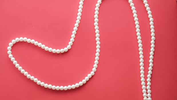 Pearl jewellery necklace on coral background.