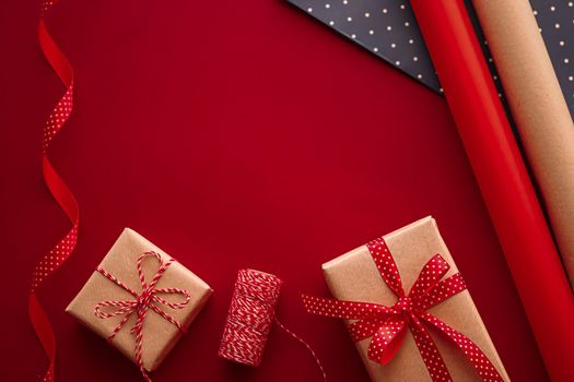 Gifts preparation, birthday and holidays gift giving, craft paper and ribbons for gift boxes on red background as wrapping tools and decorations, diy presents as holiday flat lay design.