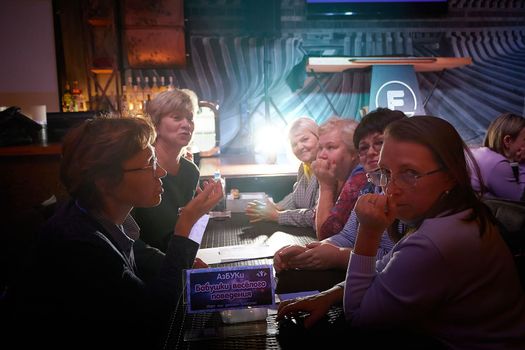 Kirov, Russia - September 13, 2022: People at table in small cafe or restaurant during intellectual game. Hungry group discussing the menu in the restaurant and waiting for waiter. Partial focus