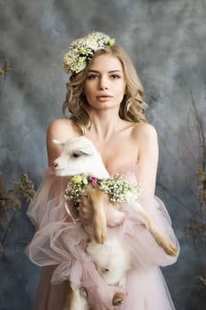 A young blonde woman in an airy pink dress with a white kid. Spring portrait of a woman