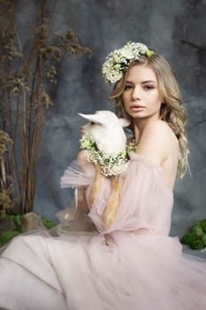 A young blonde woman in an airy pink dress with a white kid. Spring portrait of a woman