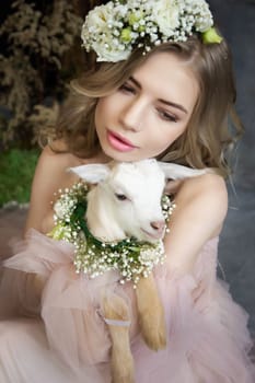 A young blonde woman in an airy pink dress with a white kid. Spring portrait of a woman