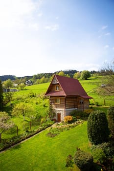 Old wooden cottage in a valley on a hill, beautiful blue sky. Landscaping. View from the window