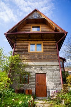 Old wooden cottage in a valley on a hill, beautiful blue sky. Landscaping. Travel, vacation