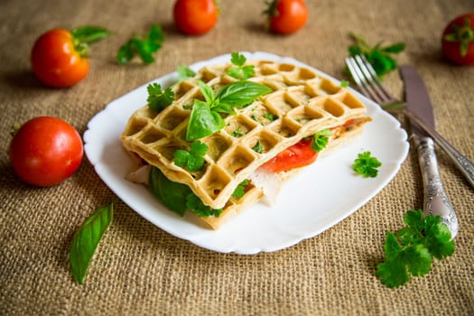 Sandwich of two egg omelettes with bacon and tomatoes inside, waffle shaped.