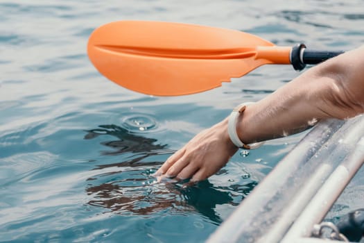 Woman in kayak back view. Happy young woman with long hair floating in transparent kayak on the crystal clear sea. Summer holiday vacation and cheerful female people having fun on the boat.