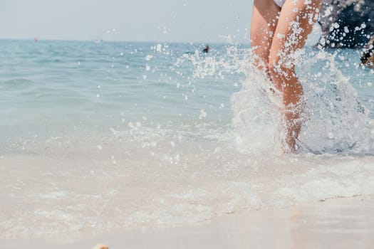 Sea beach travel - woman walking on sand beach leaving footprints in the white sand. Female legs walking along the seaside barefoot, close-up of the tanned legs of a girl coming out of the water