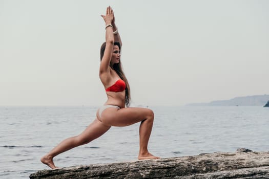 Woman meditating in yoga pose silhouette at the ocean, beach and rock mountains. Motivation and inspirational fit and exercising. Healthy lifestyle outdoors in nature, fitness concept.