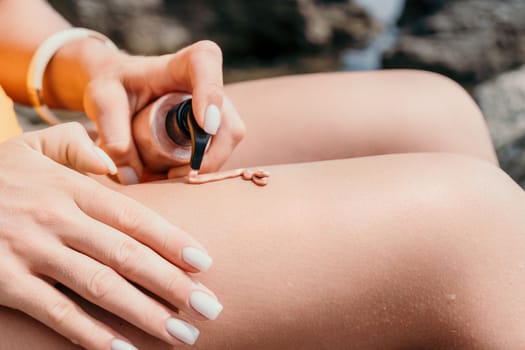 Sexy Woman in bikini apply sun protection cream on her smooth tanned legs. Skin care. Legs on the beach. Portrait of female in hat smearing moisturizing lotion. Sunblock concept.