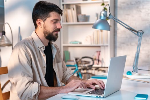 Young man student using laptop computer at home studying online. Creative professional working in office. Distance study, work from home, e-learning, business, meeting online.