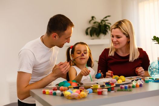 Happy easter! family mother, father and children having fun paint and decorate eggs for holiday