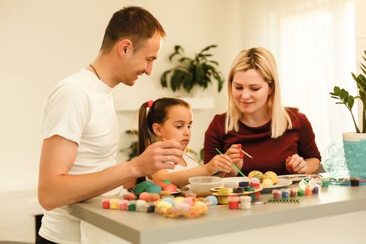 Happy easter! family mother, father and children having fun paint and decorate eggs for holiday