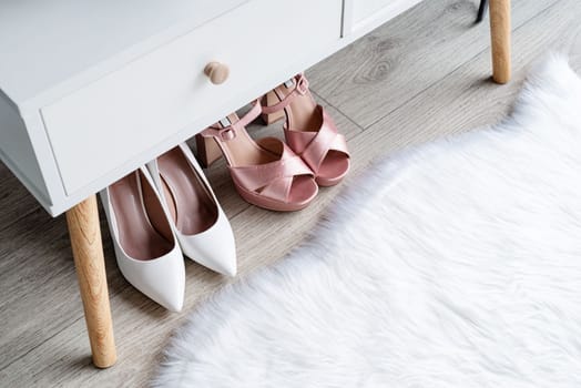 Stylish light room interior with elegant vanity table and plants, beauty and fashion. closeup of elegant high heel shoes standing under dressing table, mockup